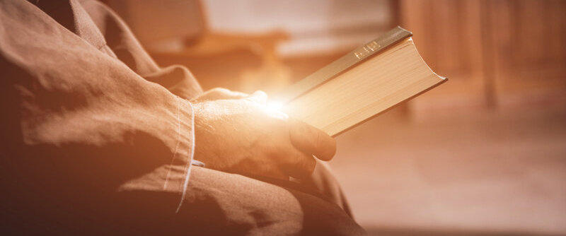 Pastor holding the Holy Bible with light reflecting off the hands.