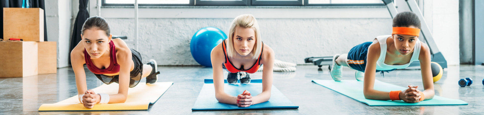 Front View of Multiethnic female athletes doing plank in fitness studio