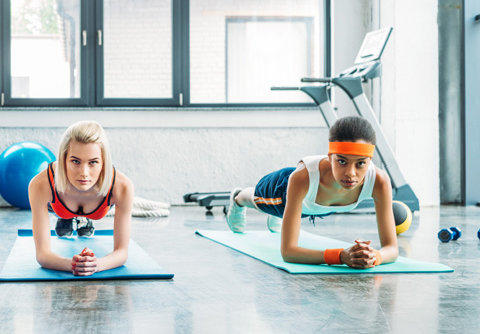 Front View of Multiethnic female athletes doing plank in fitness studio